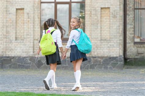 Back View Of Two Schoolgirls With School Backpack Walking Together Outdoor Sisterhood Stock