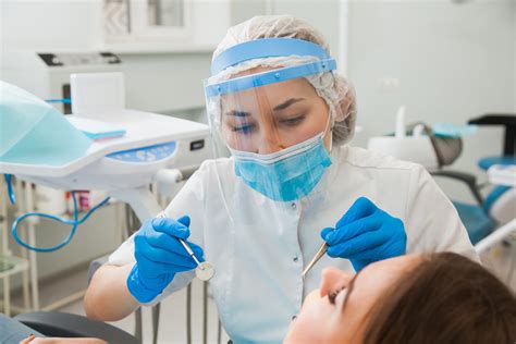 Young Female Dentist Curing Patients Teeth Filling Cavity Pearl