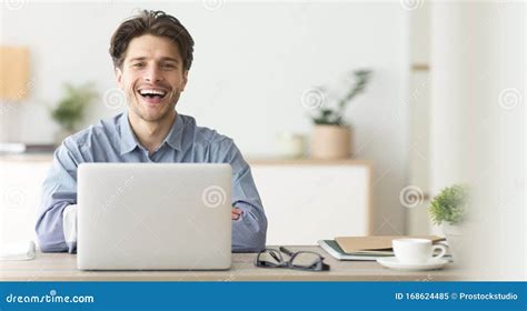 Happy Employee Smiling At Camera While Working On Laptop In Office