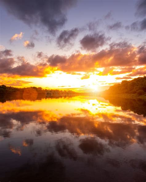 A Sunset Or Sunrise Scene Over A Lake Or River With Dramatic Cloudy