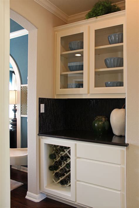 The cabinet, which is stable and sturdy, has five shelves with a capacity of 25 wine bottles. Butler's pantry with white cabinets, glass panel doors, wine rack