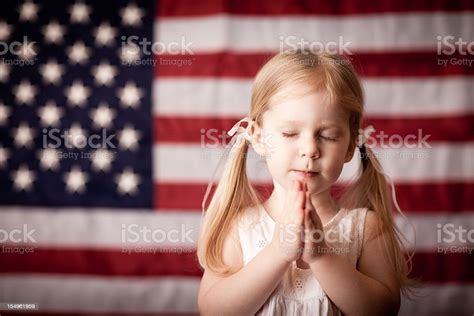 Little Girl Praying In Front Of American Flag Stock Photo And More