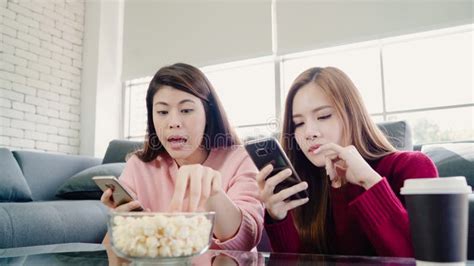 Lesbian Asian Couple Watching Tv Laugh And Eating Popcorn In Living Room At Home Sweet Couple