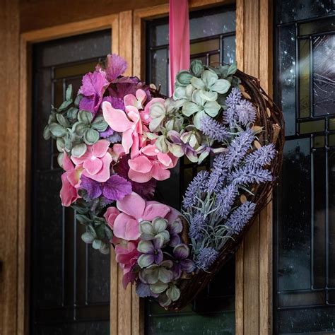 A Heart Shaped Wreath With Purple And Pink Flowers Hanging From Its