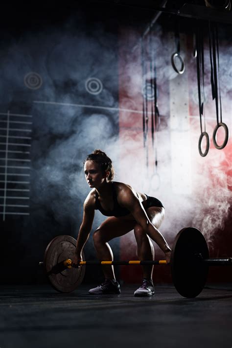 A Woman Squatting With A Barbell In Her Hands Stock Photo Images