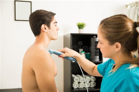 Physical Therapist Using Ultrasound Probe On Patient`s Shoulder Stock