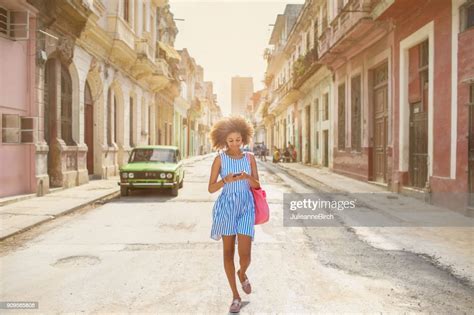 fille cubaine en regardant téléphone mobile marcher dans la rue À la havane photo getty images