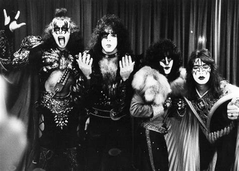 The Band Kiss Posing For A Photo In Front Of A Curtain With Their Hands Up
