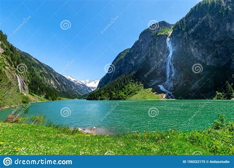 Mountain Landscape With Clear Turquoise Lake And Waterfall In The Alps