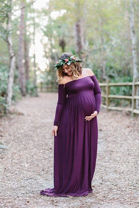 A Pregnant Woman Wearing A Purple Dress Standing In The Woods With Her Hands On Her Hips
