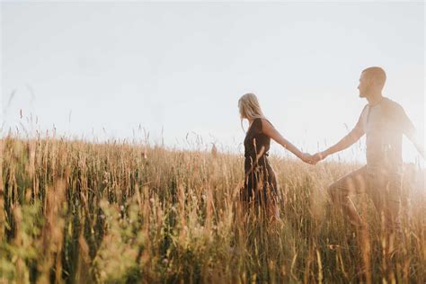 Romantic Man And Girlfriend Holding Hands In Field Of Sunlit Long Grass