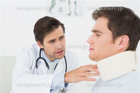 Male Doctor Examining A Patients Sprained Neck At Medical Officeの写真素材