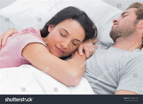 Woman Sleeping Peacefully On Her Husbands Chest In Bed Stock Photo