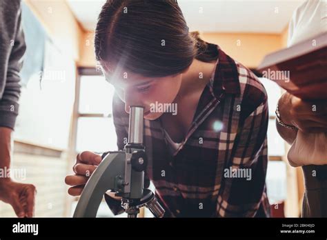 Niña De La Escuela En Clase De Ciencias Usando Un Microscopio Con