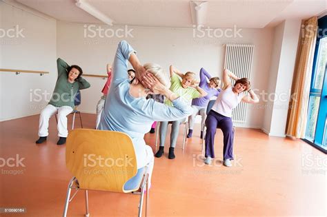 Teacher And Active Senior Women Yoga Class On Chairs Stock Photo