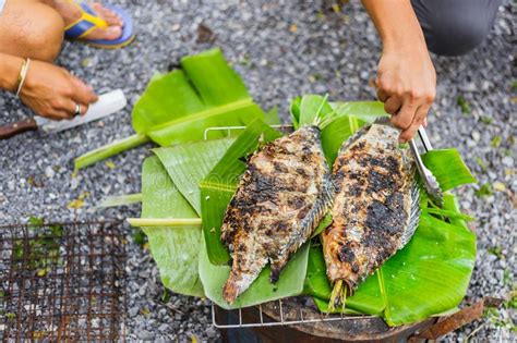 People Grilled Fresh Fish With Salt On Charcoal And Banana Leaf Stock