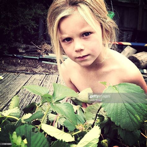 Child Wearing No Clothes Hiding In Garden Stock Photo