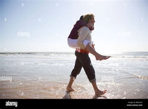 Mann Trägt Frau Auf Dem Rücken Zu Fuß Am Strand Stockfotografie Alamy