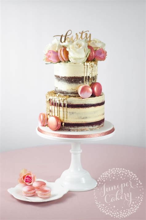 A Three Tiered Cake Sitting On Top Of A White Table Next To Pink Flowers