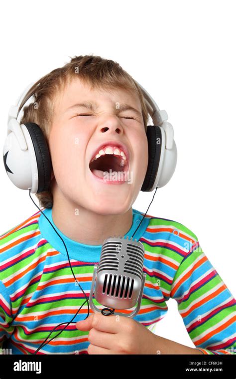 Kleiner Junge im Kopfhörer mit Mikrofon in Händen singt mit weit offenem Mund Stockfotografie