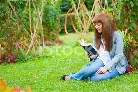 Young Woman Reading A Book Lying On The Grass Stock Photo Royalty