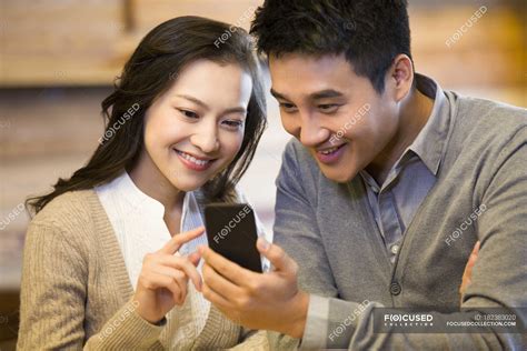 Chinese Couple Using Smartphone Together In Cafe — Dating Man Stock