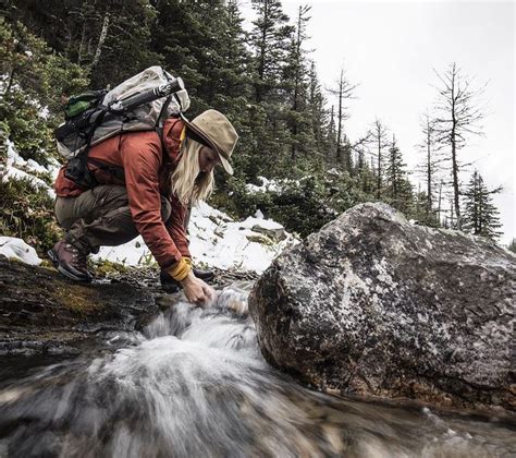 A Man With A Backpack Is Crossing A Stream