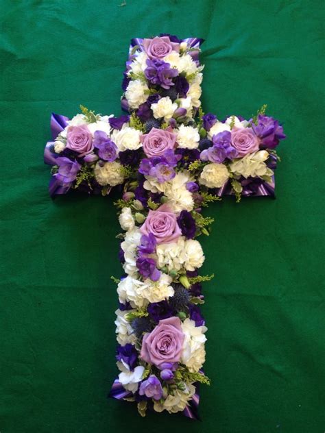 A Cross Made Out Of Flowers On A Green Background With White And Purple