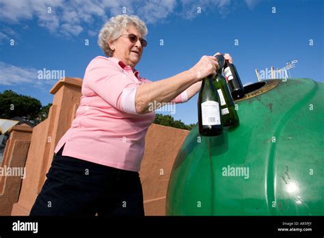 Senior Woman Throwing Glass Bottles Into Recycle Bin Stock Photo Alamy