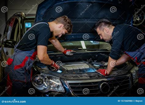 Car Mechanics Checking Under Hood In A Workshop Stock Photo Image Of