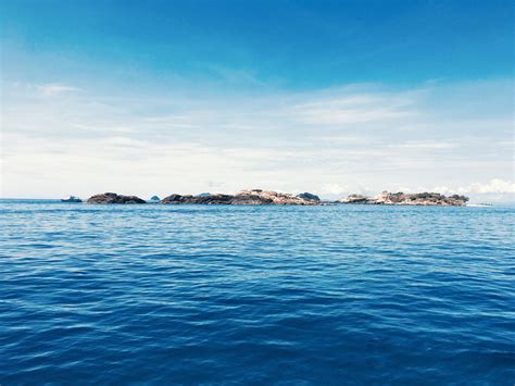 Wallpaper Calm Blue Sea With Rocks On The Horizon On