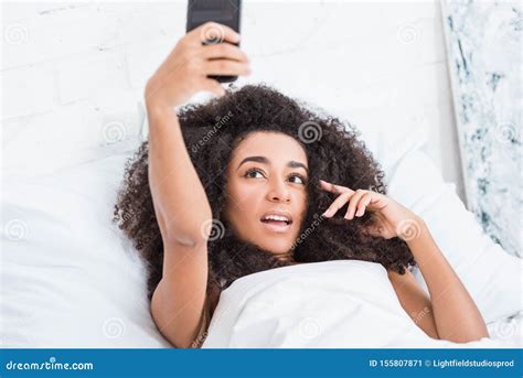 Pretty African American Girl Taking Selfie On Smartphone In Bed During Morning Time Stock Image