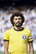 a man with curly hair wearing a yellow shirt and standing in front of a ...