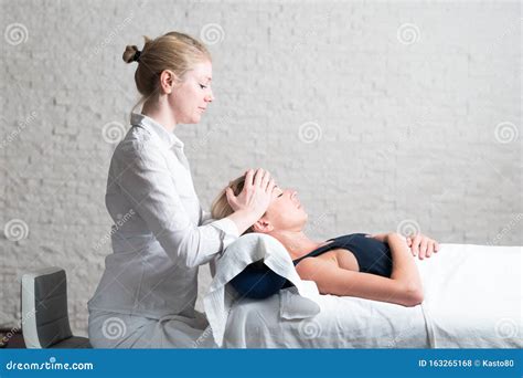 Professional Female Masseur Giving Relaxing Massage Treatment To Young