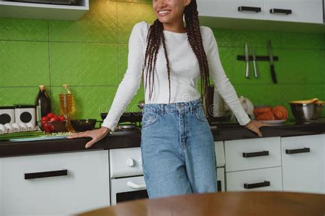 positive woman smiling while standing in her kitchen happy mixed race female preparing food