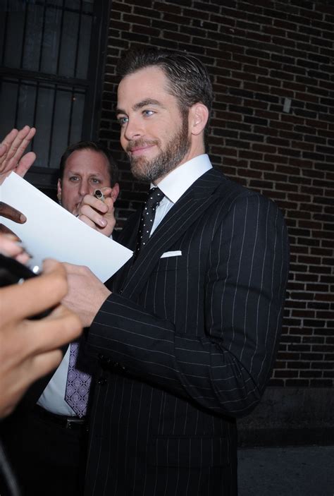 A Man In A Suit Signing Autographs For Fans