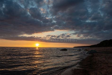 Colorful Sunset Over Calm Sea Beach With Dark Blue Water And Dramatic