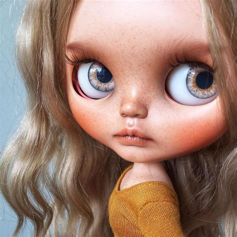 A Doll With Long Blonde Hair And Big Blue Eyes Is Posed For The Camera