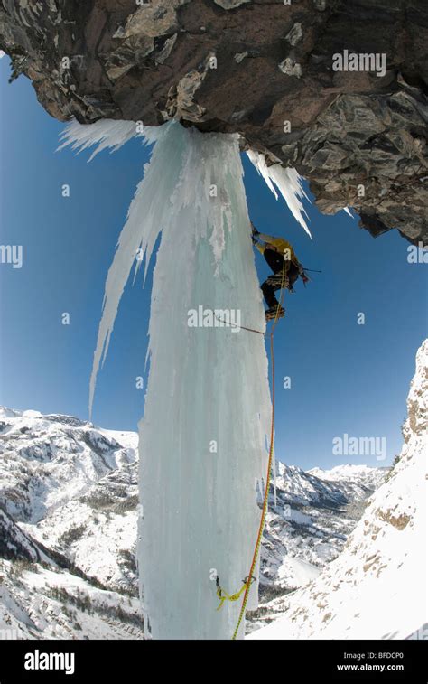 A Professional Male Climber Ascends A Frozen Waterfall Pillar While Ice