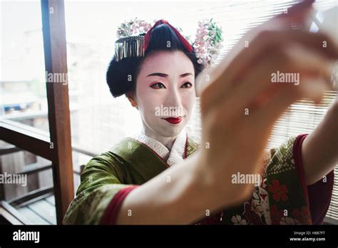 A Woman Dressed In The Traditional Geisha Style Wearing A Kimono And Obi Taking A Selfie Of