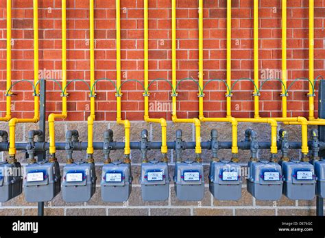Row Of Natural Gas Meters With Yellow Pipes On Building Brick Wall