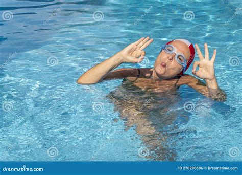 A Woman Is In A Swimming Pool Wearing Goggles And Swim Cap Sticking