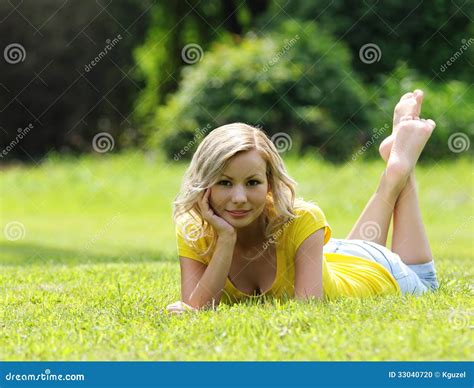 Blonde Girl Laying On The Grass And Smiling Looking At The Camera
