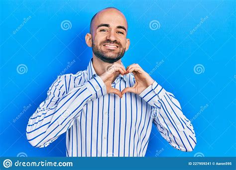 Young Bald Man Wearing Elegant Clothes Smiling In Love Doing Heart Symbol Shape With Hands Stock