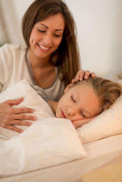 premium photo happy attentive mother is lying in bed and hugging her sleeping daughter