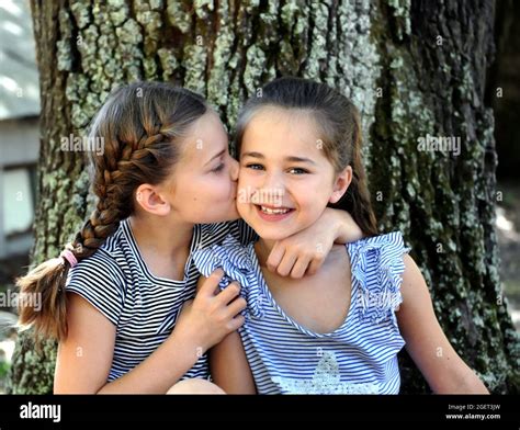 two sisters sit outside besides a tree they show their friendship and affection for each other