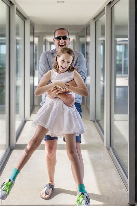 Father And Daughter Laughing In A Hallway Of A Modern Home By Stocksy