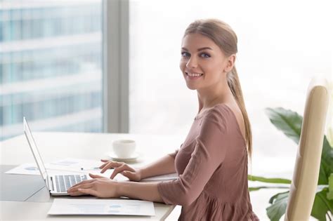 Empresaria Sonriente Joven Que Se Sienta En El Escritorio De Oficina