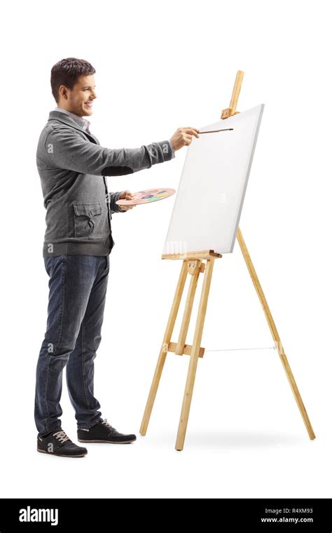 Full Length Shot Of A Smiling Young Man Painting On A Canvas Isolated