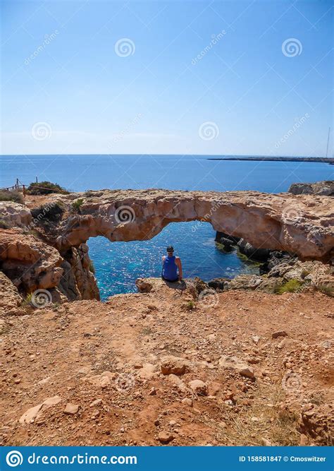 Cyprus Young Man Sitting In Front Of A Rocky Arch Stock Image Image